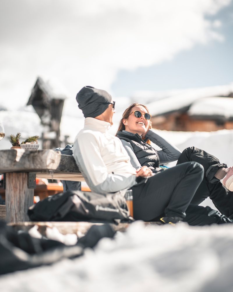 A couple enjoys the winter sun and the view during a stop at the Seiser Alm.