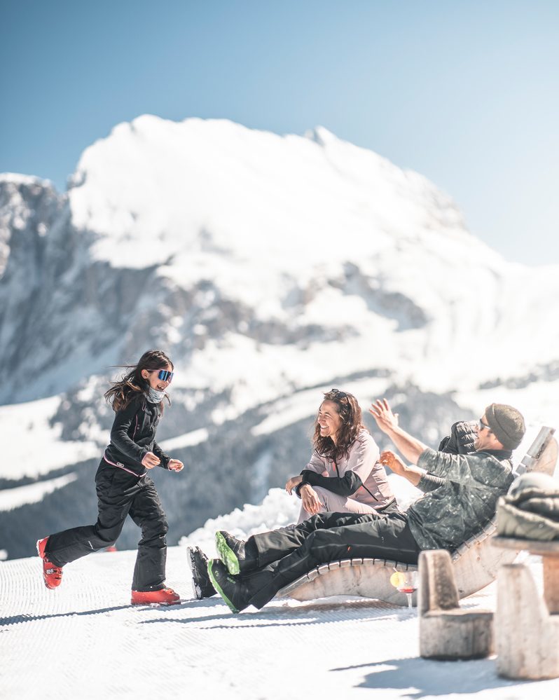 A happy family enjoys the winter sun against the backdrop of the Dolomites.