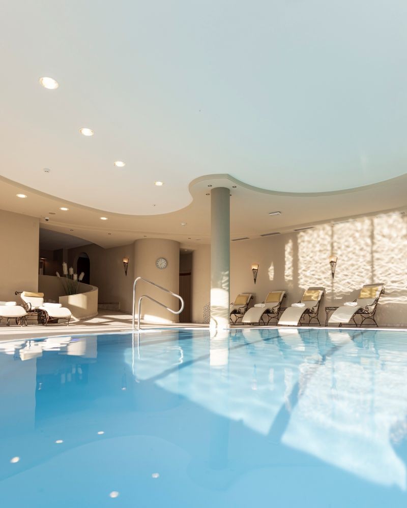 Luminosa piscina coperta nell'area benessere dell'Hotel Baumwirt, dotata di comodi lettini.
