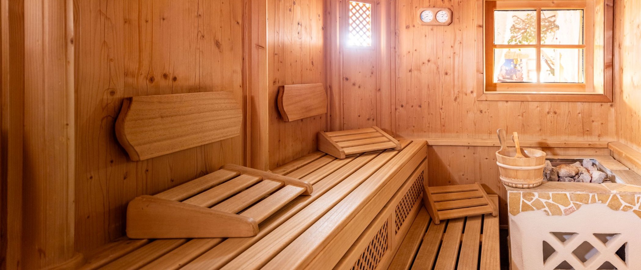 Panorama-Aufnahme der gemütlichen Sauna mit Holzbänken und Kopfstützen im Wellnessbereich.