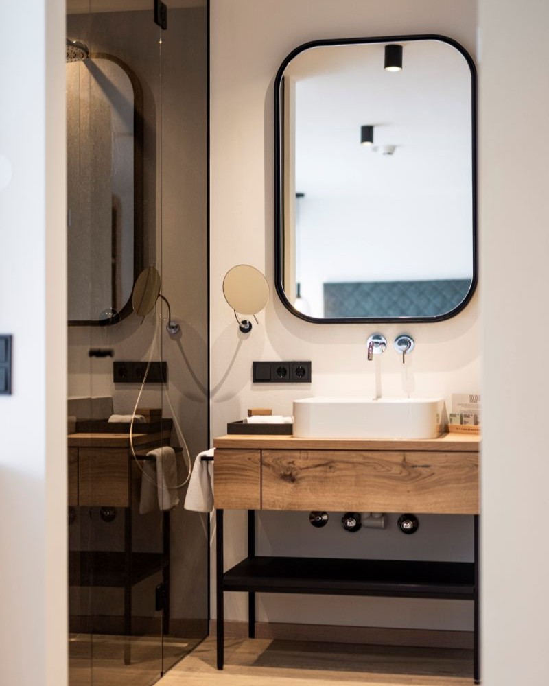 Bagno dal design moderno presso l'Hotel Baumwirt, con elementi in legno naturale e linee pulite.